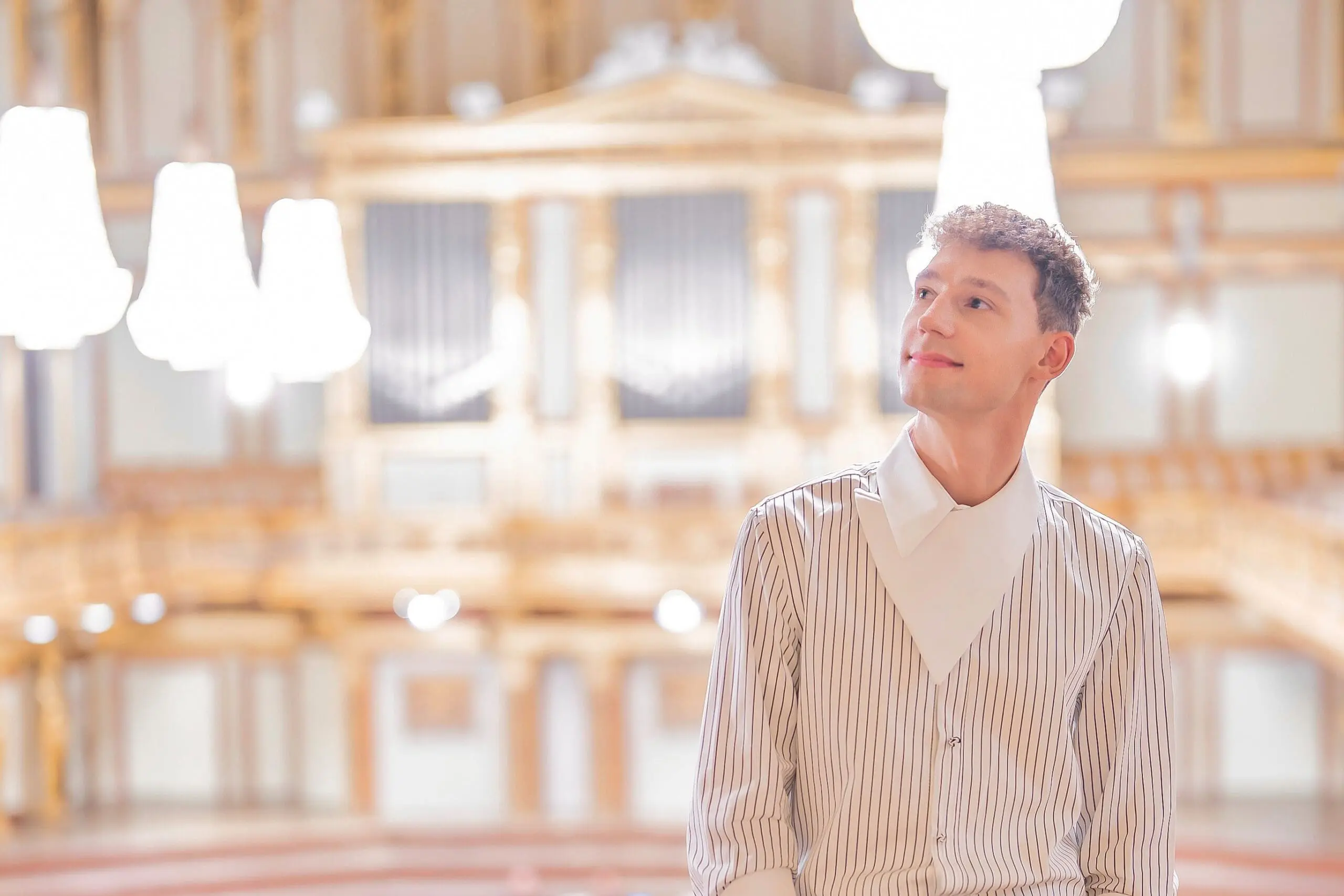 Portrait von Lukas Hasler. Blonder Mann am Balkon des Großen Saals, im Hintergrund die Orgel