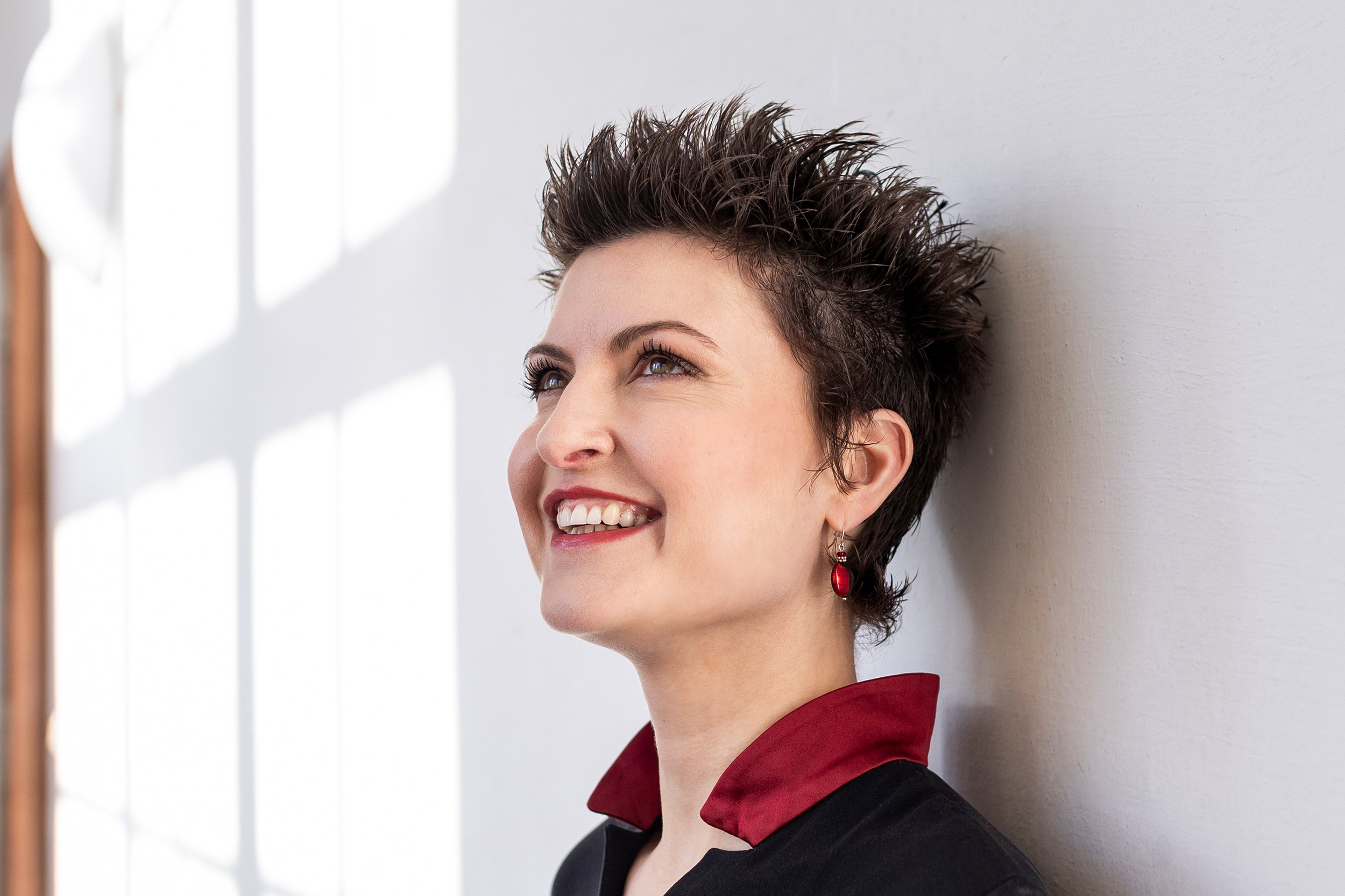 Portrait von Angela Metzger. Lachende Frau mit kurzen schwarzen Haaren