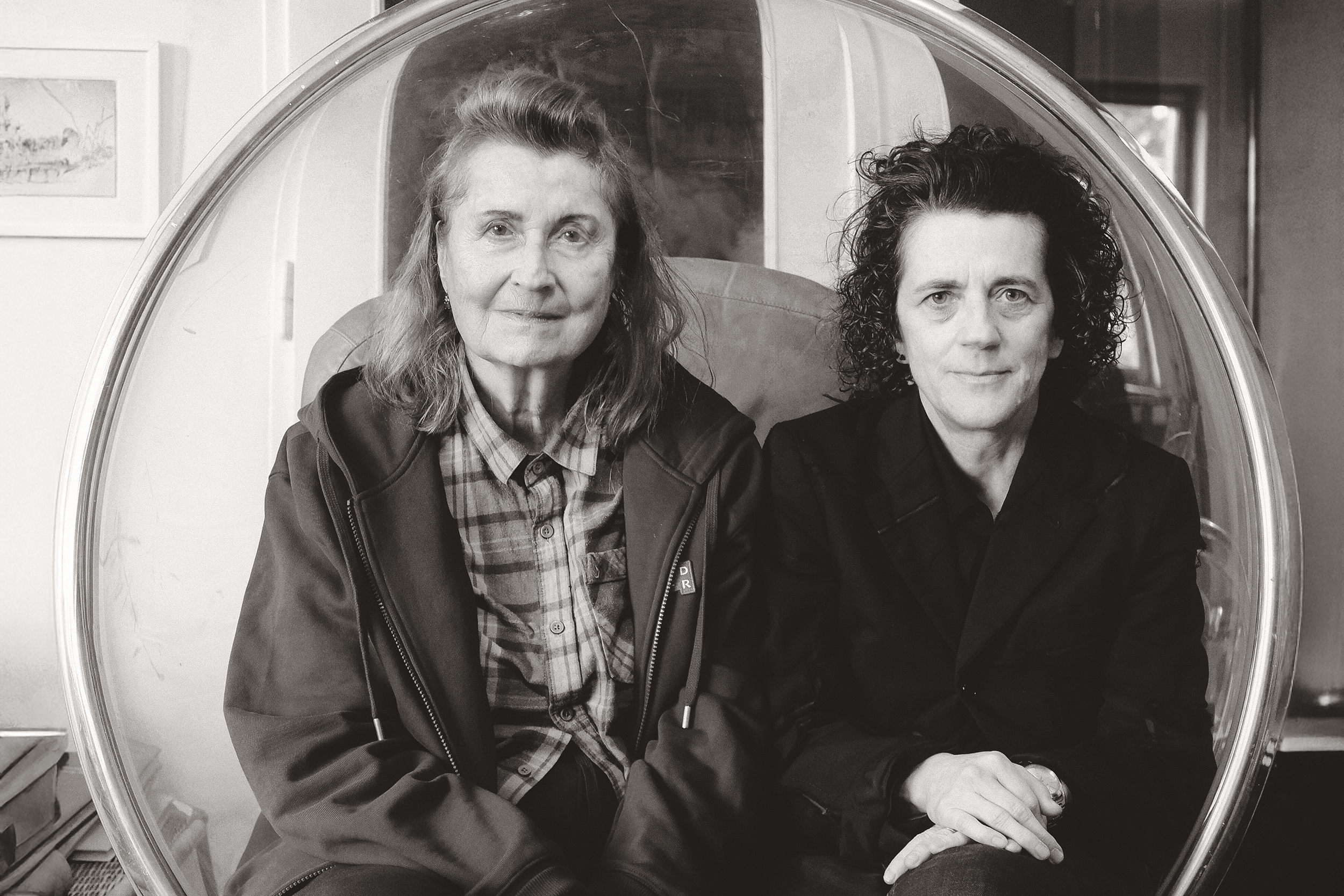 Schwarz-weiß Portrait von Elfriede Jelinek und Olga Neuwirth in einer durchsichtigen Kugel sitzend